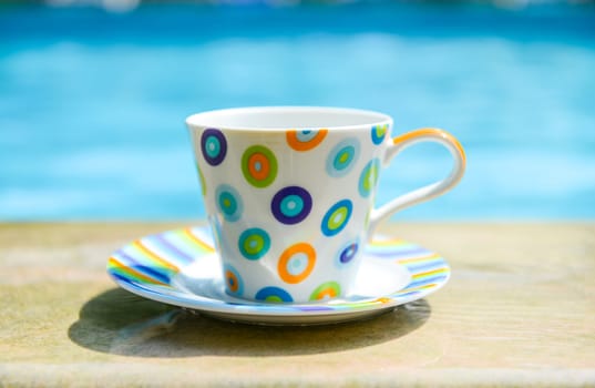 Colorful cup of coffee on the pool