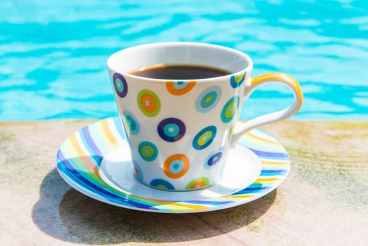 Colorful cup of coffee on the pool