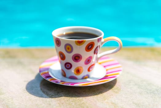 Colorful cup of coffee on the pool