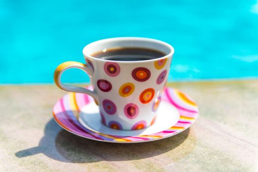 Colorful cup of coffee on the pool