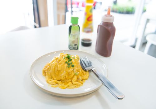 creamy omelet on rice in white plate on the table