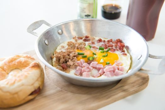  Healthy breakfast - fried eggs, ham, bacon, pork in the pan and bread on wooden plate. Selective focus