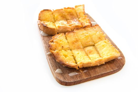 Bread toast and condensed milk on wooden plate over white background