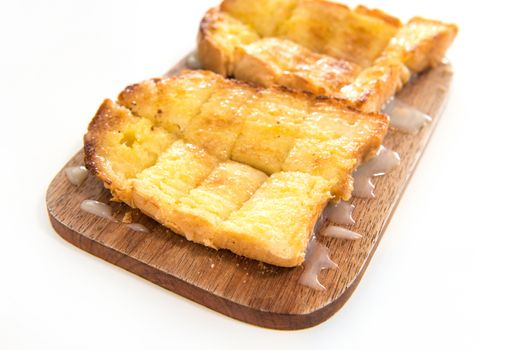 Bread toast and condensed milk on wooden plate over white background