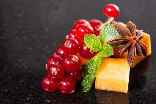 Assortment of delicious cheese and fruits on black