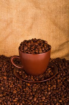 Cup full of coffee beans on the cloth sack