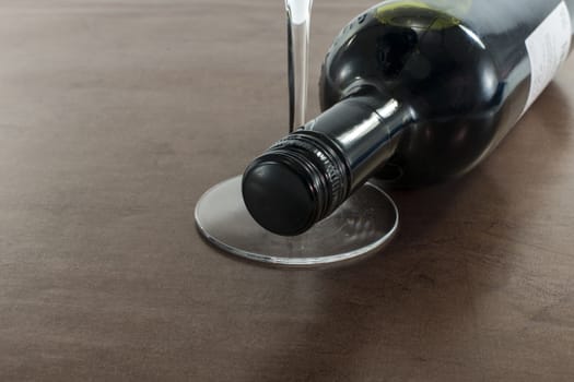 red bottle of wine with glass on golden background