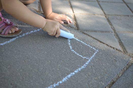 Child hand drawing with chalk on the ground