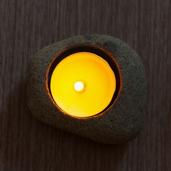 Candle in stone for decoration, over wooden table
