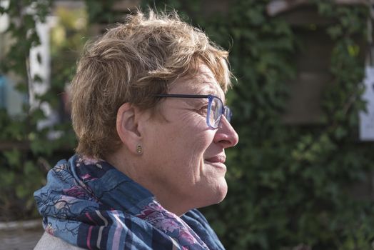 woman with golden hair and glasses thinking in the garden