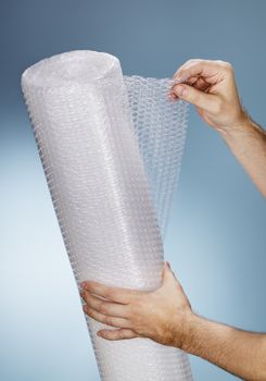 Man holding a roll of plastic bubble wrap.