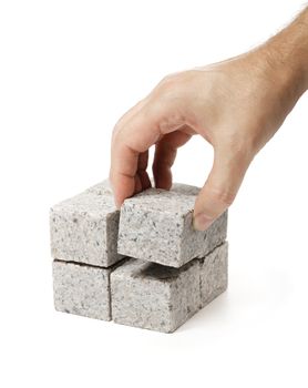 Man building a cube of smaller cubes made of granite rock.