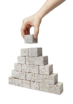 Man building pyramid made of small blocks of granite rock.