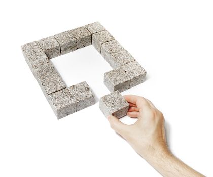 Man finishing a square made of small blocks of granite rock.