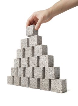 Man building pyramid made of small blocks of granite rock.