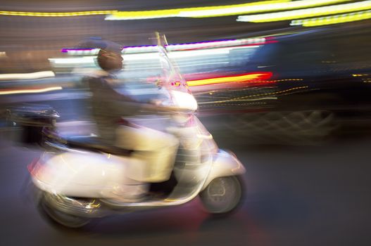 Abstract blurry image of a scooter driving at night.