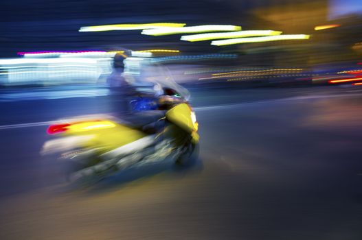 Abstract blurry image of a scooter driving at night.