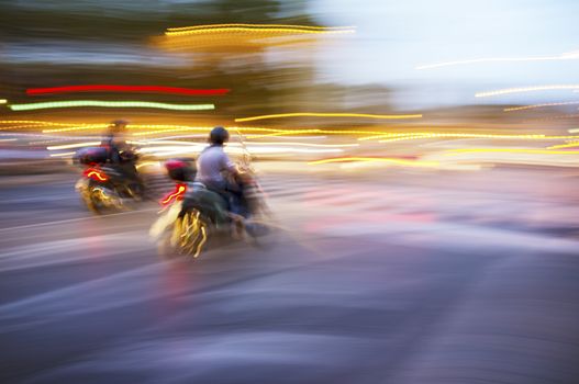 Abstract blurry image of a scooters driving at night.