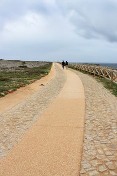 Couple walking on a long path with dark stormy sky above
