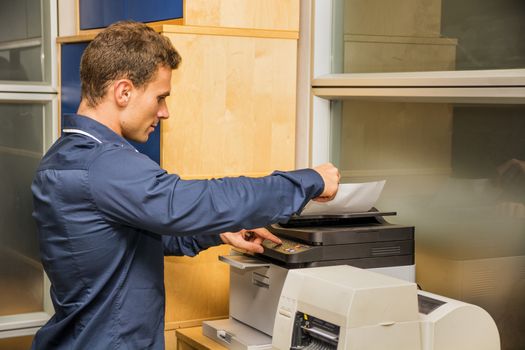 Young Handsome Man Operating High-Tech Photocopier Machine at the Office.