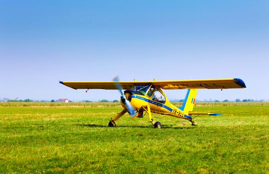 Brasov, Romania - August 12, 2010: Retro yellow airplane on a green grass field preparing to take off