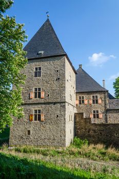 Age castle tower against blue sky and other historic parts of the building.
