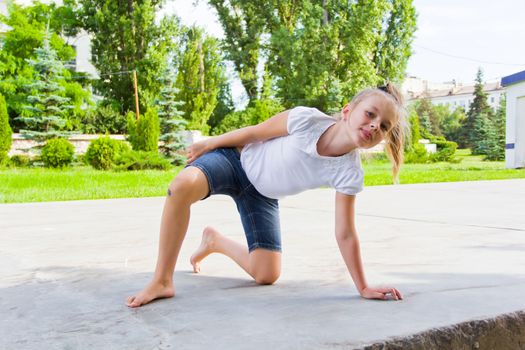Cute girl draws chalk on asphalt in summer