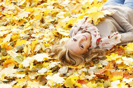 Portrait of beautiful young woman lying outdoors in autumn park