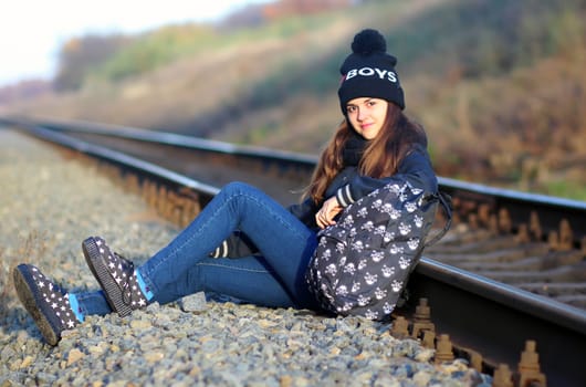 A girl sitting near the railway at sunset