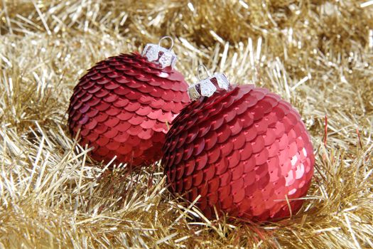 Two red Christmas sequin baubles on golden tinsel.