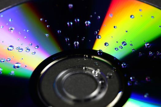 Photo of a compact disc with water drops isolated on black background. Objects photography.