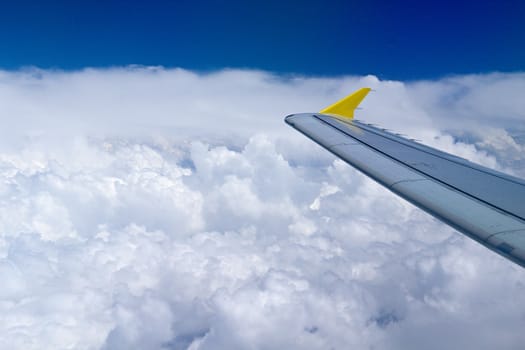 Photo shows details of white clouds, blue sky and plane.