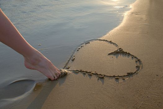 Photo shows a detail of the  heart written in the sand.
