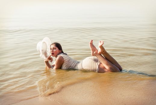 Woman in a striped retro bathing suit in the white hat posing against the sea