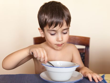 Little boy eats with a spoon from a plate