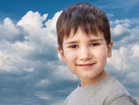 Happy little boy smiling on blue sky with white clouds background