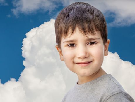 Happy little boy smiling on blue sky with white clouds background