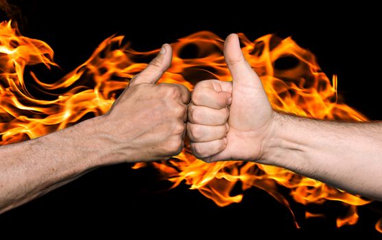 Friendship sealed with fire concept. Two men bumping fists with thumbs up against the fire flames
