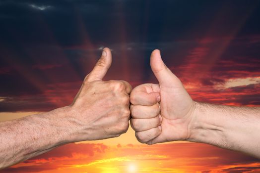 Partnership. Thumbs up sign on sunset sky background