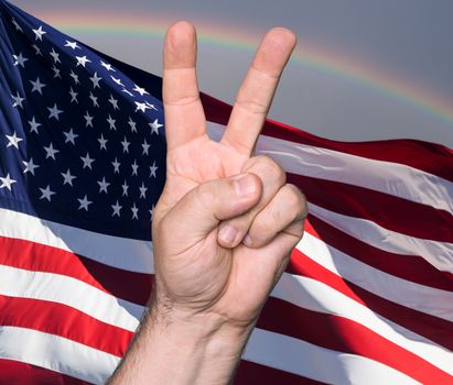Patriotic concept.  Man hand showing the sign of victory and peace against of USA flag
