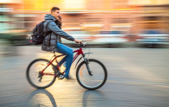 UZHGOROD, UKRAINE - OCT 22, 2013: Cyclist on the streets of Uzhgorod. People hurrying about their business. Image in motion blur style.