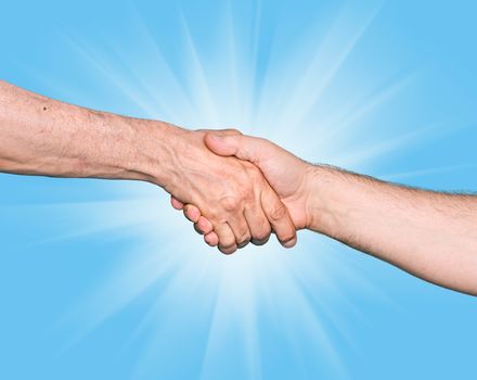 Shaking hands of two male people against the blue sky and sunlight