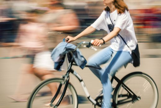 Hot day in the city. Cyclist in traffic on the city roadway. Intentional motion blur