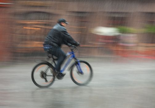 Downpour. Wet cyclist rides through the streets on a rainy day . Intentional motion blur