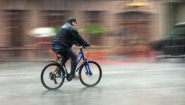 Downpour. Wet cyclist rides through the streets on a rainy day . Intentional motion blur