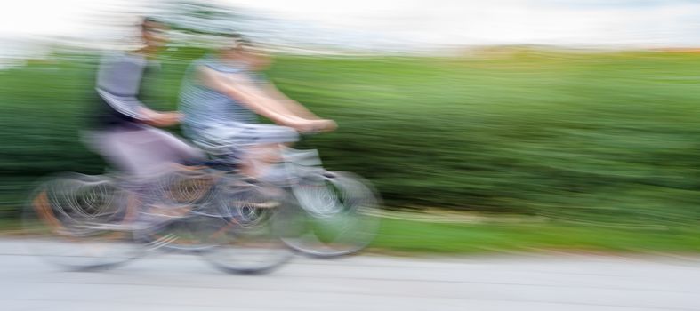 Two teenagers cyclists in traffic on the city roadway. Intentional motion blur