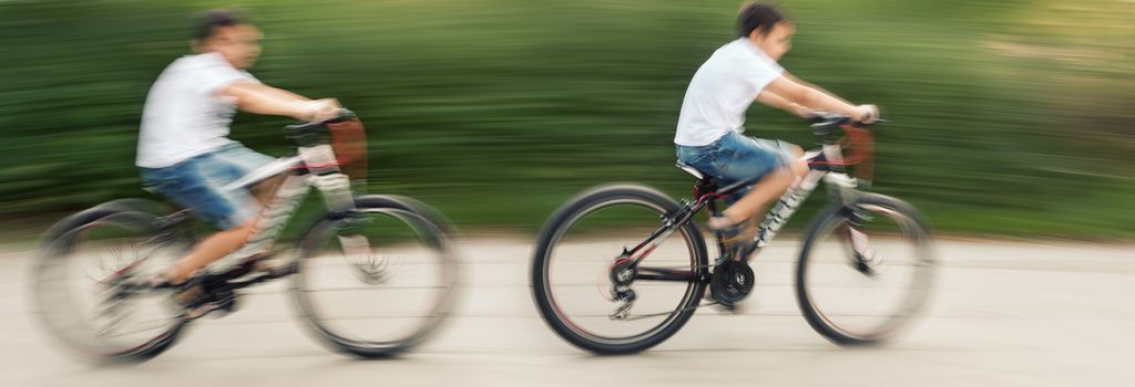 Two teenagers cyclists in traffic on the city roadway. Intentional motion blur