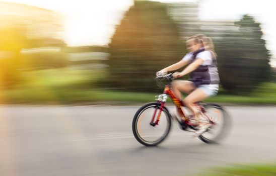 Girl cyclist in traffic on the city roadway. Intentional motion blur