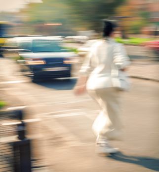 Woman crossing the street at a crosswalk. Intentional motion blur