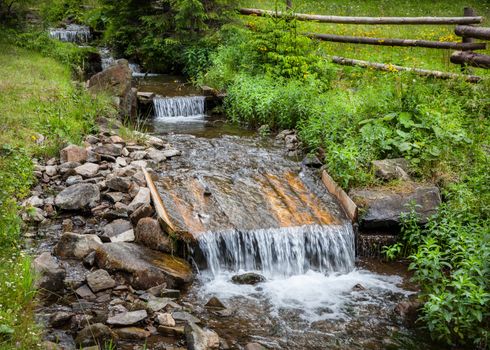 Small stream with water cascade flowing through idyllic landscape, Ukraine
